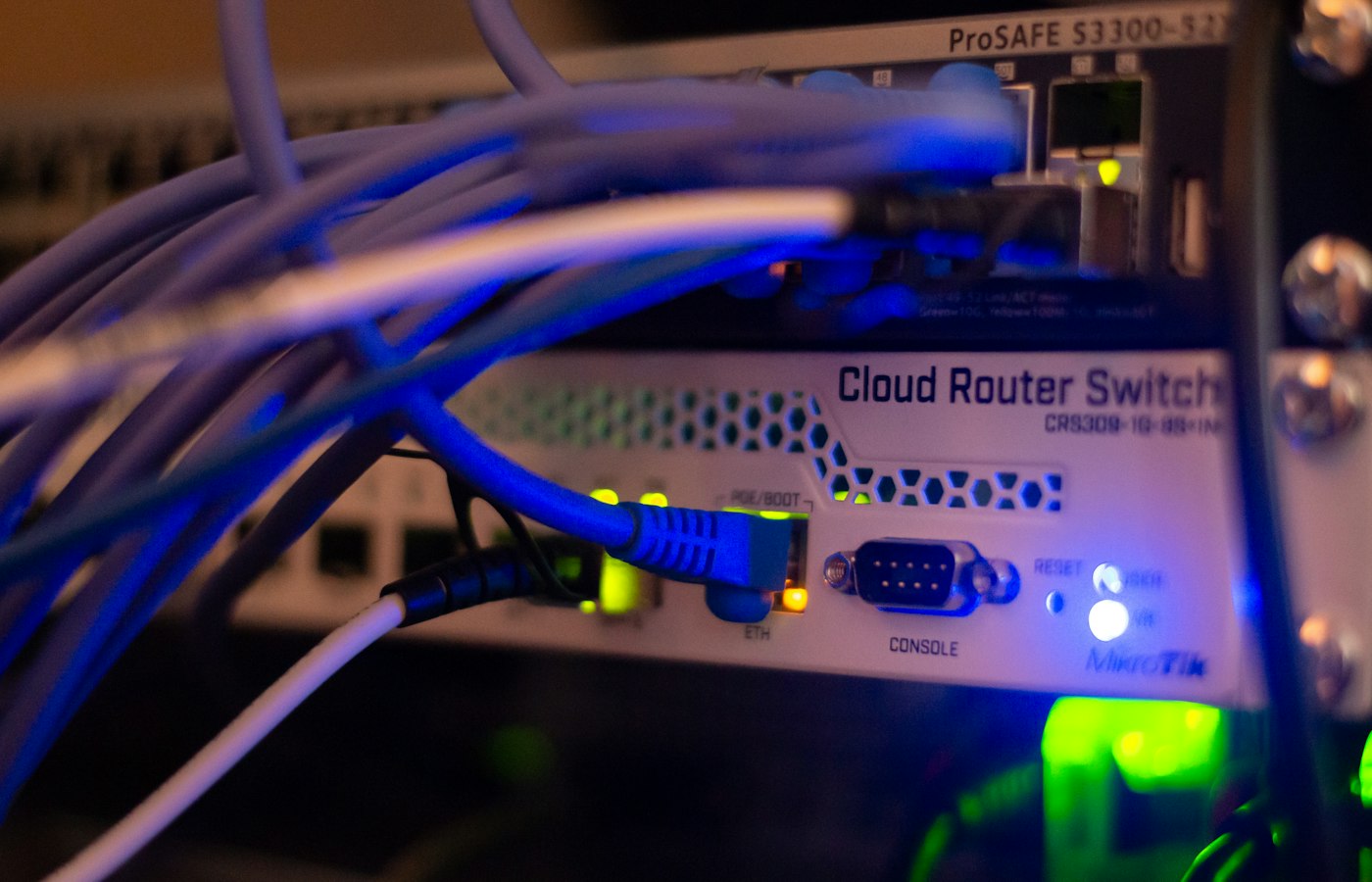 Blue and violet network cabling patched into a cloud router switch, lit in low light