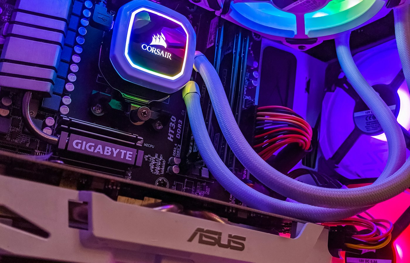 Inside a PC case lit by violet and magenta RGB lighting, showing a liquid cooler