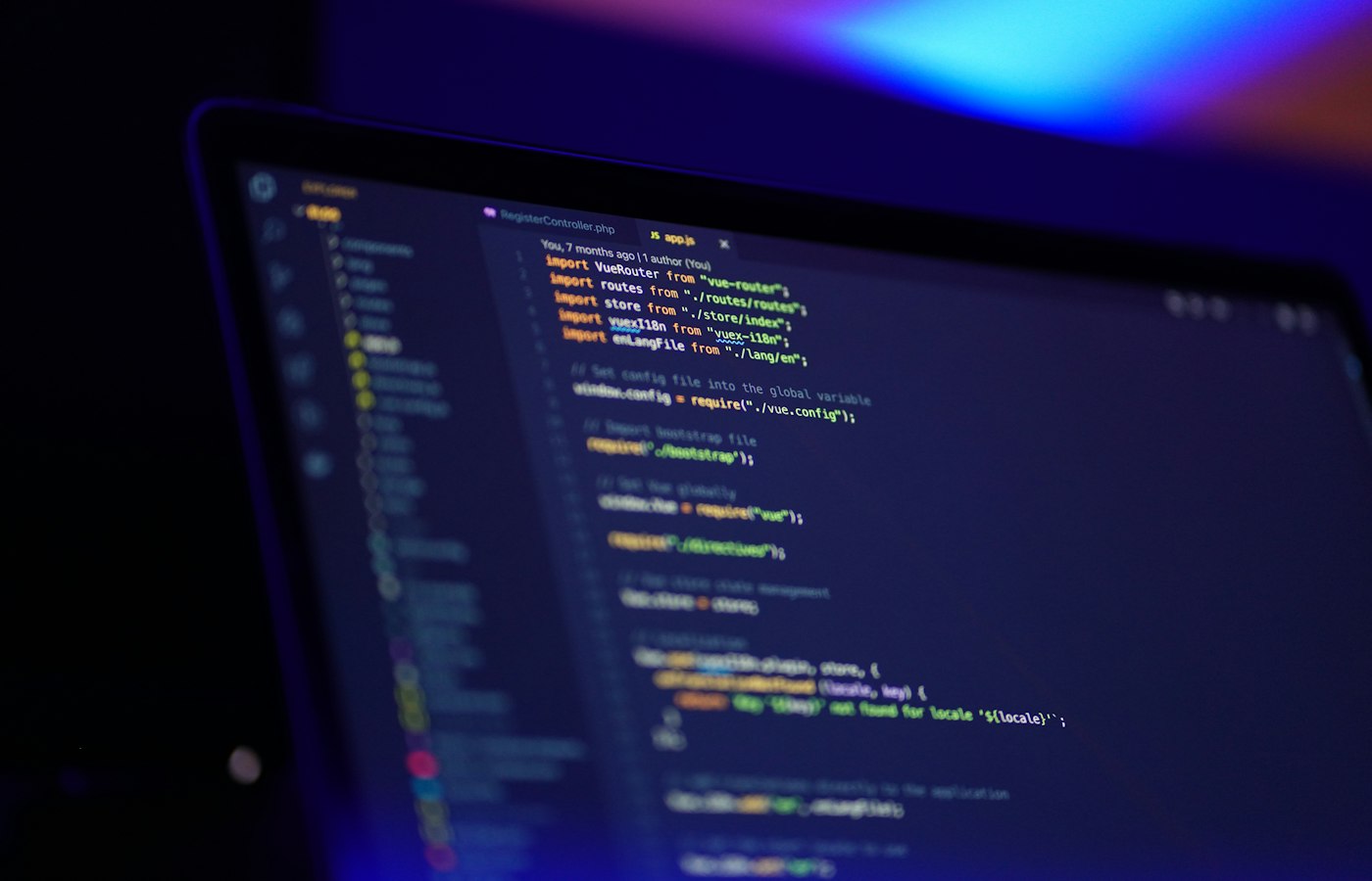 Source code on a laptop screen washed in blue and violet light