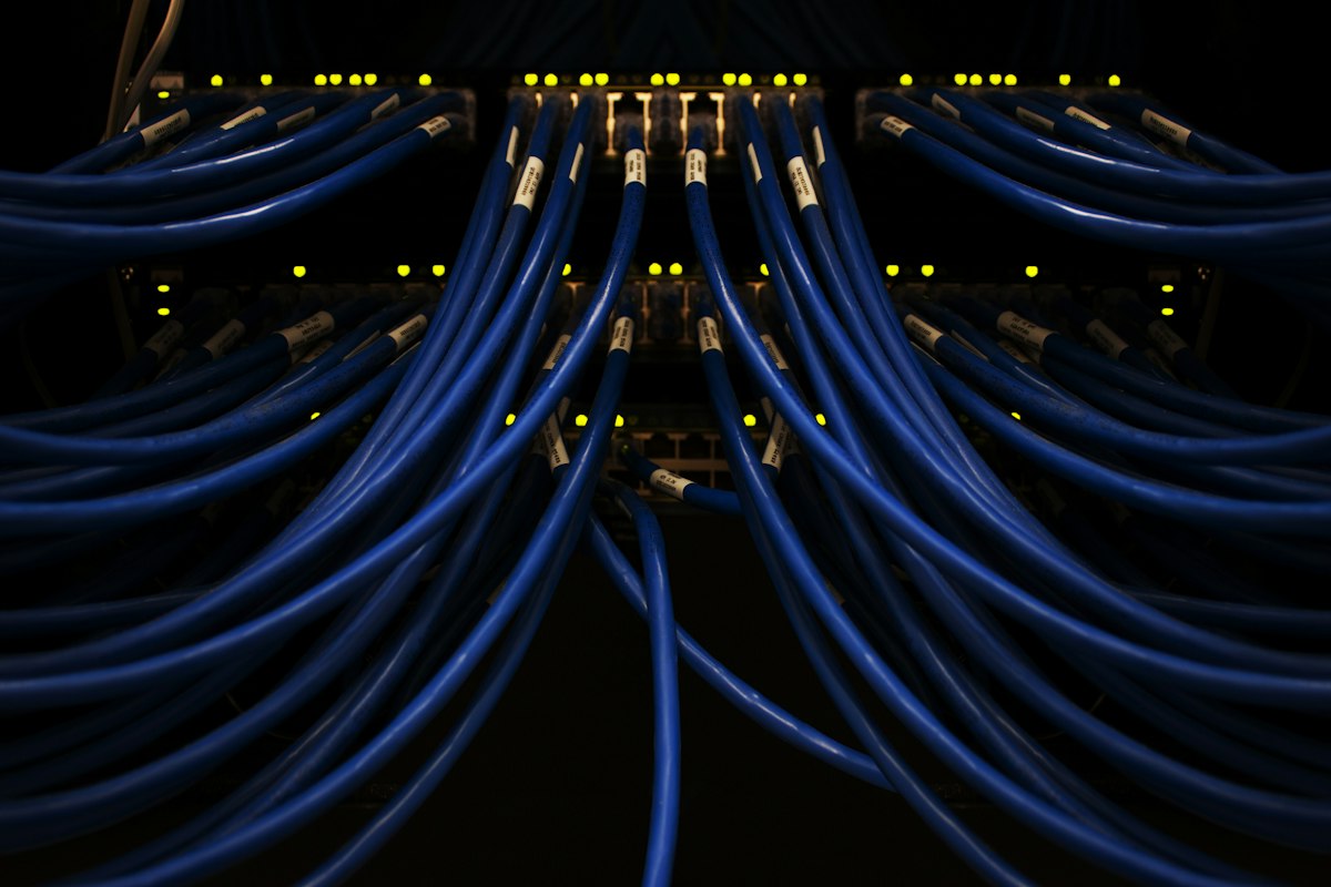 Rows of server racks in a dark data centre, threaded with fibre cabling