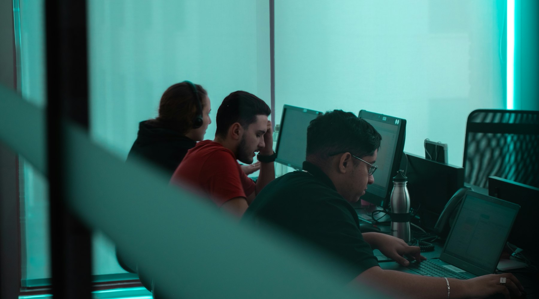 Editorial team working at monitors in a dark, teal-lit newsroom