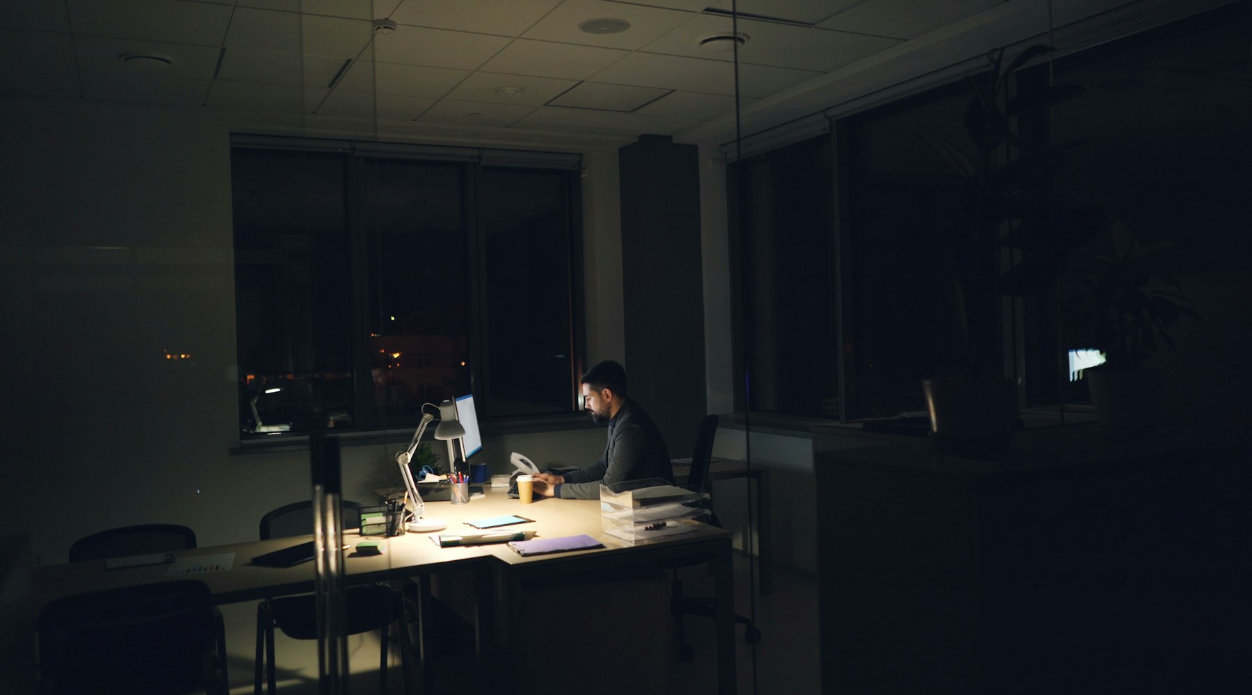 A darkened newsroom at night with a single desk lit by monitor glow